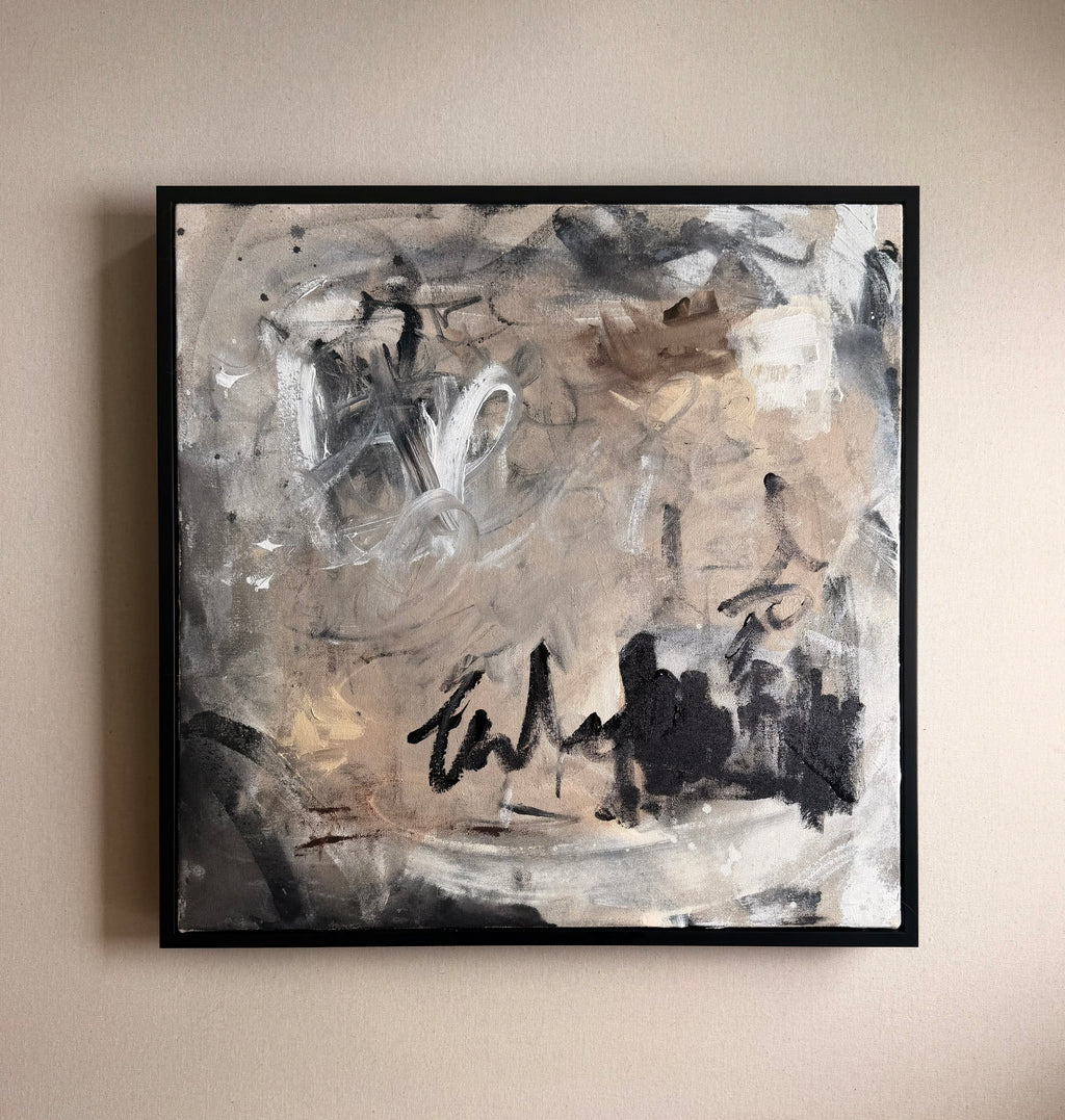 Abstract painting with black, white, and gray tones on a beige wall.
