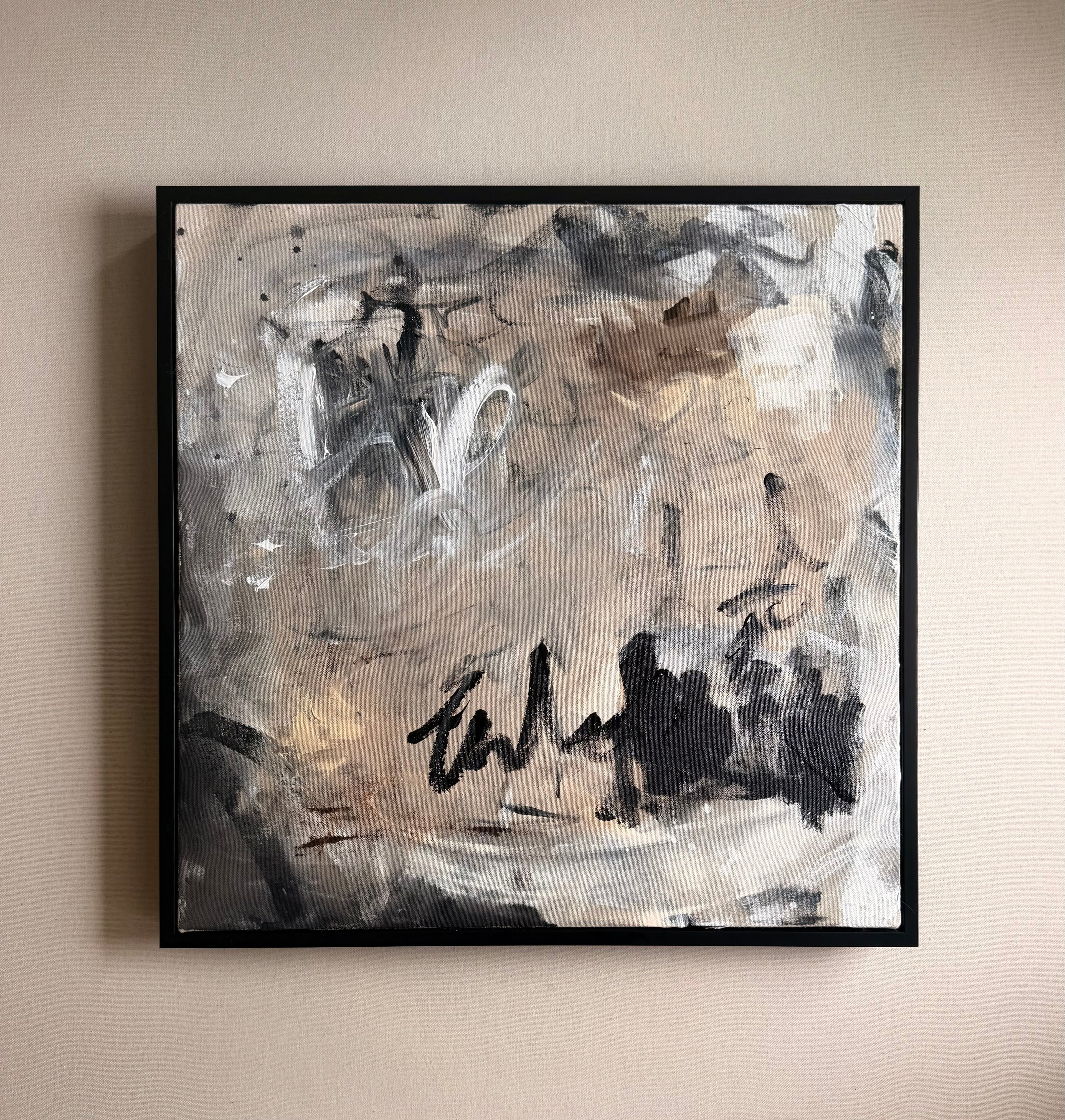 Abstract painting with black, white, and gray tones on a beige wall.